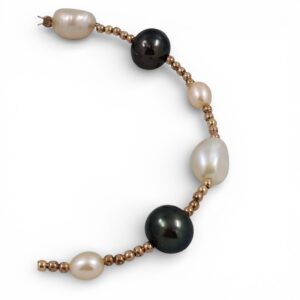 Bracciale artigianale con perle naturali rosa e nere Tahiti alternate a piccole sfere dorate su sfondo bianco.