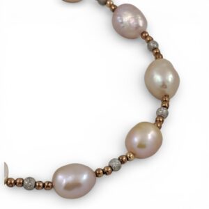 Bracciale artigianale con perle naturali rosa di diverse dimensioni e sfere in argento satinato alternate su fondo bianco.