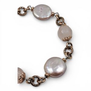 Bracciale in argento rosato con tre grandi perle rosa piatte e due sfere di quarzo rosa alternate su maglia intrecciata.